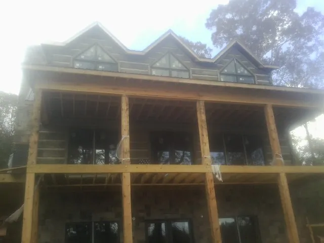 Dormers and porch framing on a large log home under construction — Roof Coating work by our crew in North Bend