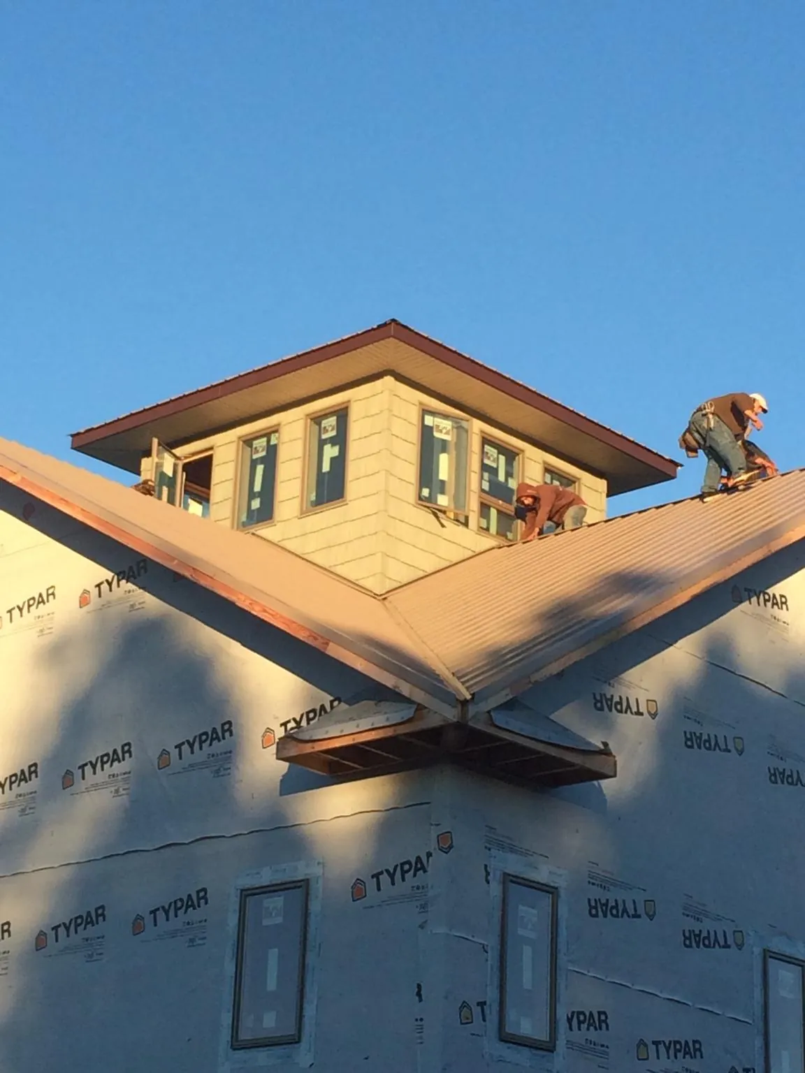 Roofers working around a rooftop cupola on a new metal roof at sunset — Roof Waterproofing in North Bend by Roofing Brothers